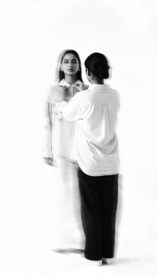 Northkind shoot in progress: a stylist adjusting a model's outfit against a white studio backdrop.